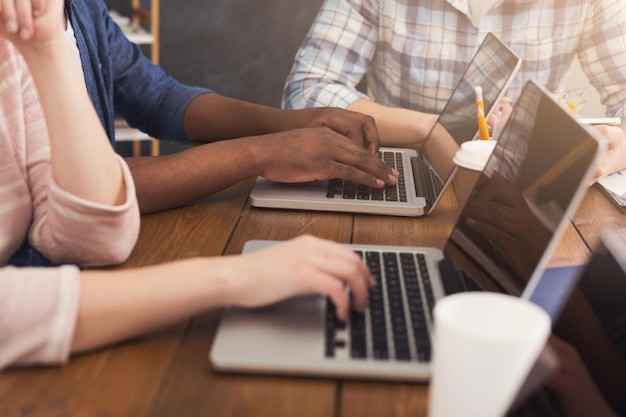 Foto onherkenbaar team van jonge programmeurs die werken in een softwareontwikkelingsbedrijf, typen op laptops, nieuwe games of apps testen, ruimte kopiëren