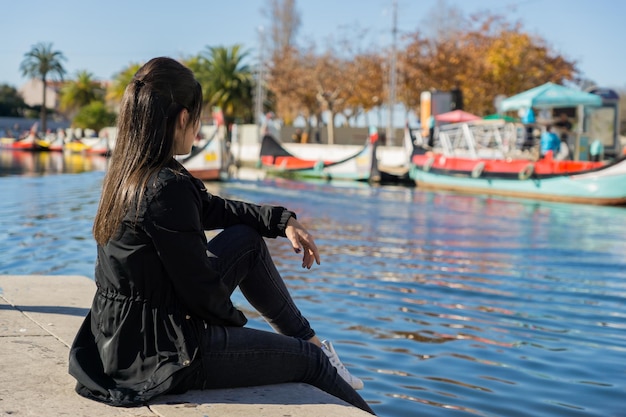 Onherkenbaar toeristenmeisje dat naar de typische boten van de waterkanalen van Aveiro Portugal kijkt