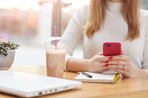 Onherkenbaar vrouw met rode slimme telefoon in haar handen