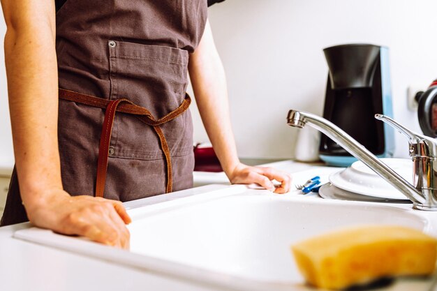 Onherkenbaar vrouwenfiguur in bruin werkschort in keuken bij aanrecht