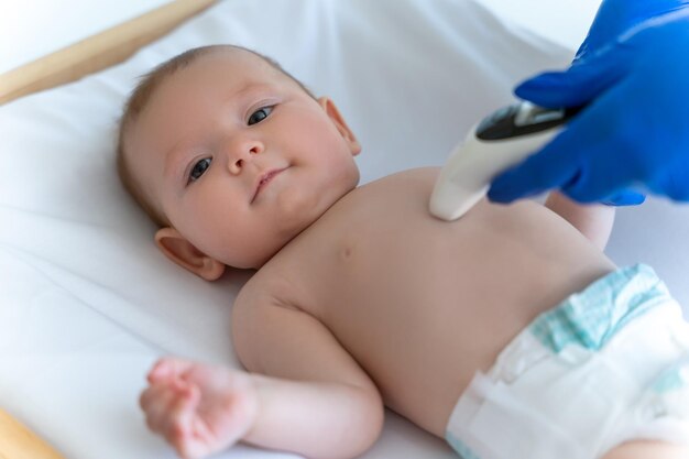 Onherkenbare arts of verpleegster die de temperatuur van de baby met een digitale thermometer controleert