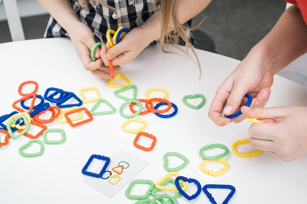 Foto onherkenbare bijgesneden vrouw meisje handen verbinden kleurrijke ketting element puzzel constructor autisme en adhd stoornis