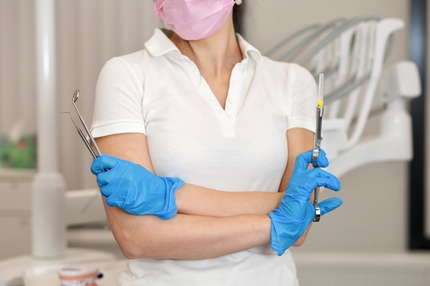 Onherkenbare handen van vrouwelijke tandartsvrouw die in handschoenen medische stomatologie tandhulpmiddelen houden