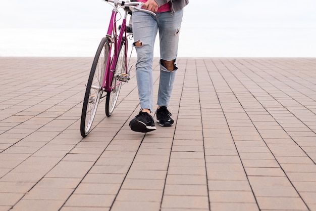 Onherkenbare jonge man die een fiets voortduwt