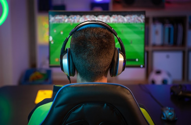 Onherkenbare jonge man die thuis sportspellen op de computer speelt