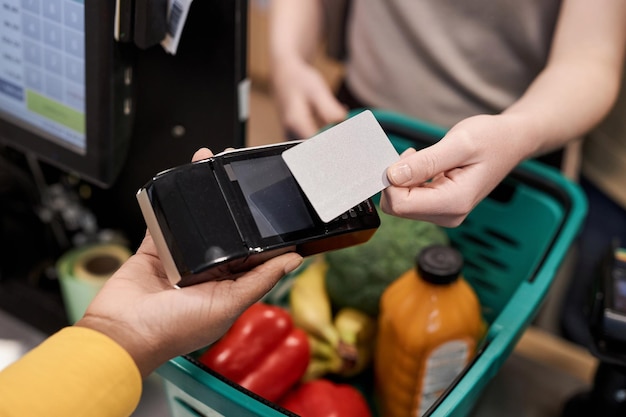 Foto onherkenbare jonge vrouw die creditcardmodel in supermarkt gebruikt