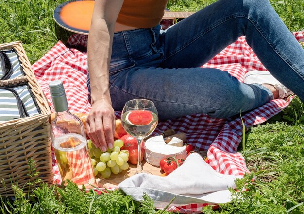 Onherkenbare jonge vrouw in het park buiten op een zonnige dag, genietend van zomerdromen en wijn drinken