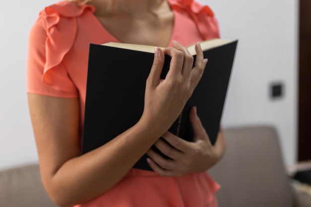 Onherkenbare jonge vrouw met een boek in een mooie jurk