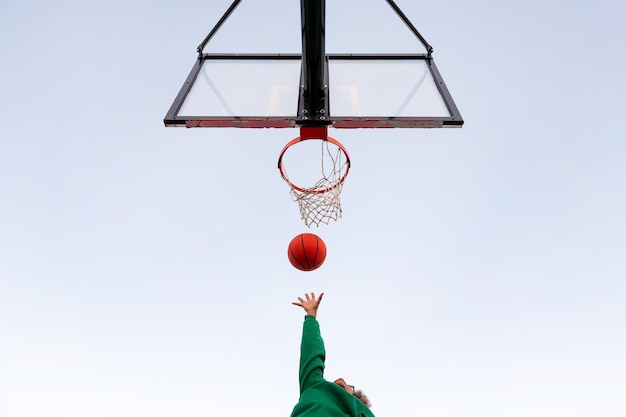 Onherkenbare Latijns-vrouw spelen in een basketbalveld van onderaf gezien met de lucht op de achtergrond concept van stedelijke sport buitenshuis kopieer ruimte voor tekst