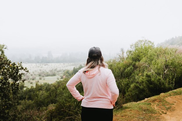 Onherkenbare latin plus size vrouw, een heuvel beklimmen en wandelen in een prachtig landschap.