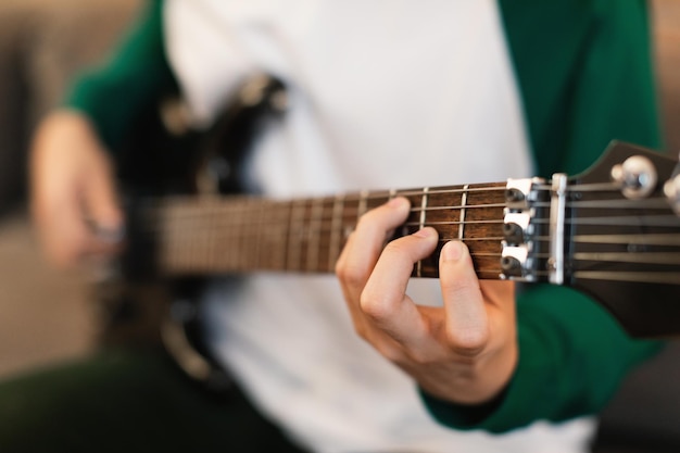 Onherkenbare man die elektrische gitaar speelt binnenshuis Close-up van handen