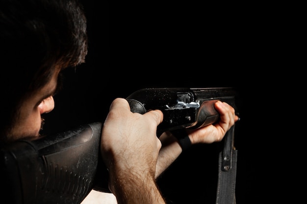 Foto onherkenbare man gericht met een jachtgeweer in het donker
