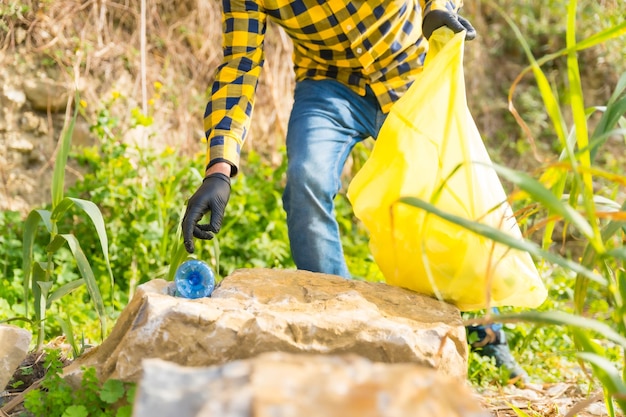 Onherkenbare man hand oppakken van een plastic fles in een bos Ecologie concept recycling