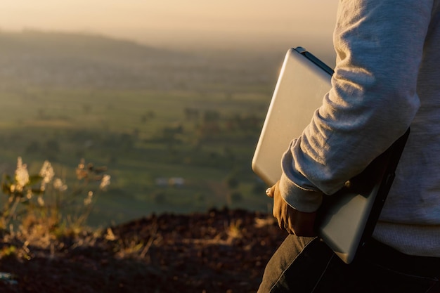 Onherkenbare man met een laptop die bij zonsopgang loopt