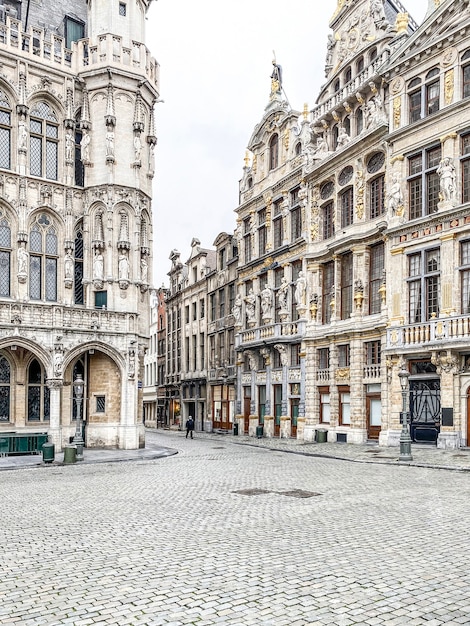 Onherkenbare persoon die alleen op de Grote Markt van Brussel loopt met een beschermend masker tijdens de crisis COVID-19