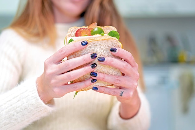 Onherkenbare persoon die thuis een groentesandwich in de keuken kookt en het klaarmaakt