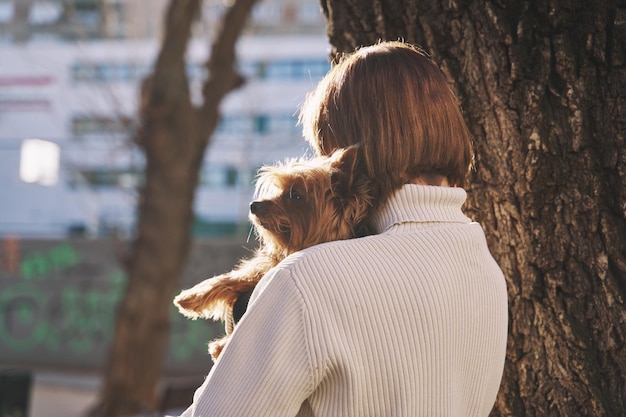 Onherkenbare vrouw die haar hond van de terriër van Yorkshire koestert