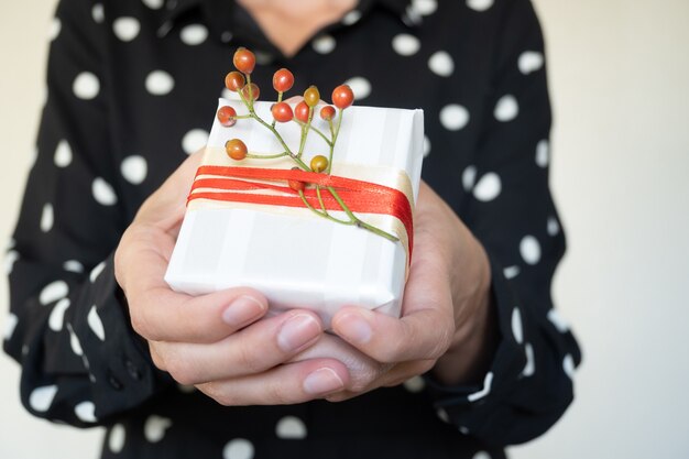 Onherkenbare vrouw die handgemaakt kerstcadeau, selectieve focus, lichte achtergrond en kopieerruimte aanbiedt