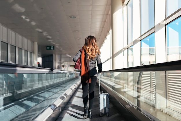 Onherkenbare vrouw die met koffer op de luchthaven loopt. Bedrijfsconcept.