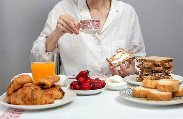 Onherkenbare vrouw die ontbijt in pyjama's thuis heeft