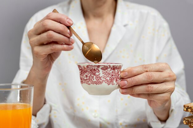 Onherkenbare vrouw die ontbijt in pyjama's thuis heeft