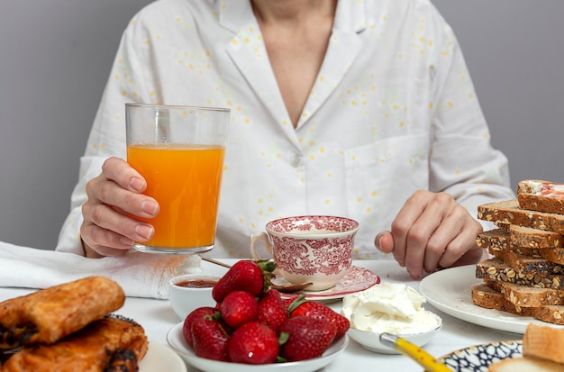 Onherkenbare vrouw die ontbijt in pyjama's thuis heeft