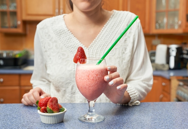 Foto onherkenbare vrouw die op het punt staat een gezonde smoothie te drinken gemaakt met amandelmelk en aardbeien