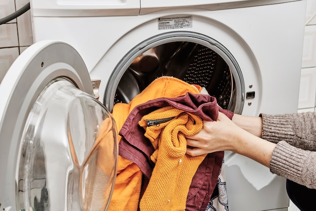 Onherkenbare vrouw die vuile was in de wasmachine wast