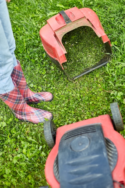 Onherkenbare vrouw met een grasmaaier gras in huis tuin, tuinman vrouw aan het werk, mooie zomerse landschap, zonlicht, geweldig ontwerp voor alle doeleinden, tuinieren concept