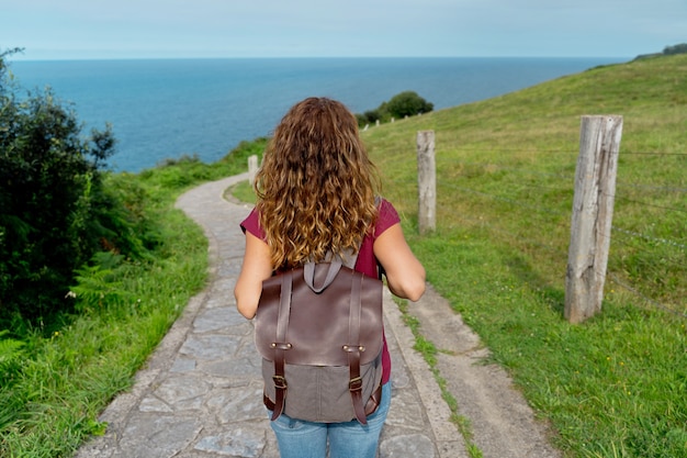 Foto onherkenbare vrouw met rugzak in groene route. horizontale weergave van backpacker op avontuurlijke reis. mensen en reisbestemmingsconcept.