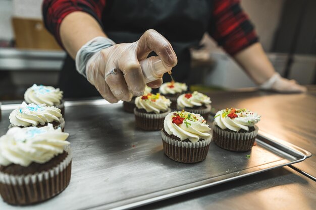 Onherkenbare vrouw versiert chocolade cupcake met hagelslag roestvrijstalen tafelprofessional