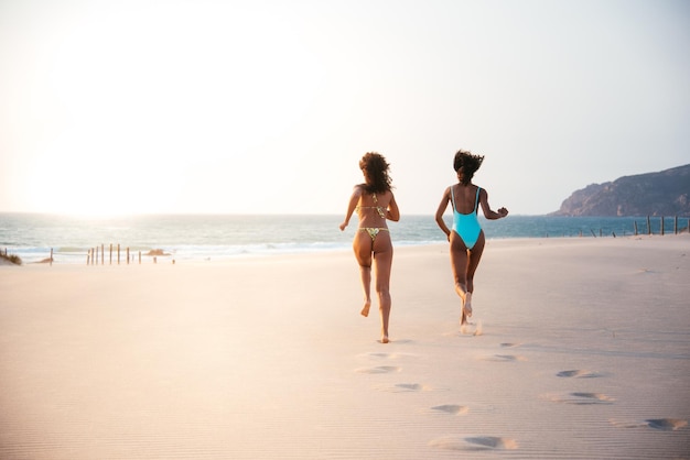 Onherkenbare vrouwen genieten op het strand in zwempak