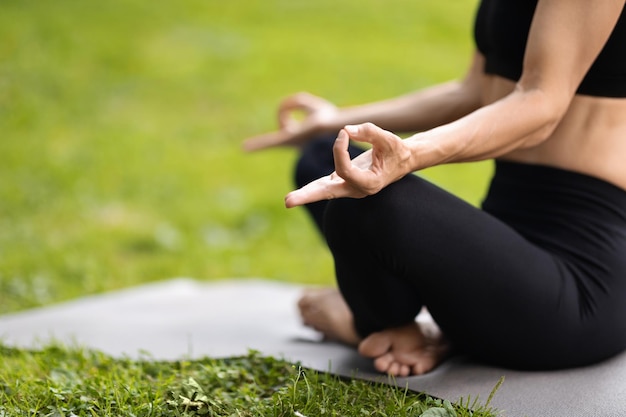 Onherkenbare yogavrouw die meditatie heeft bij park