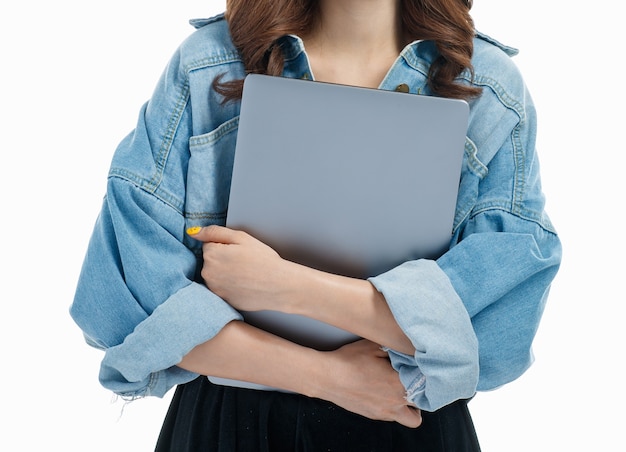 Onherkenbare zakenvrouw in jeans kleedt zich met laptop, ze glimlacht, studio-opname op witte achtergrond, concept voor nieuwe generatie zakenvrouw.