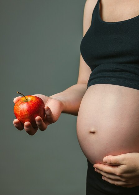 Onherkenbare zwangere vrouw met een rode appel