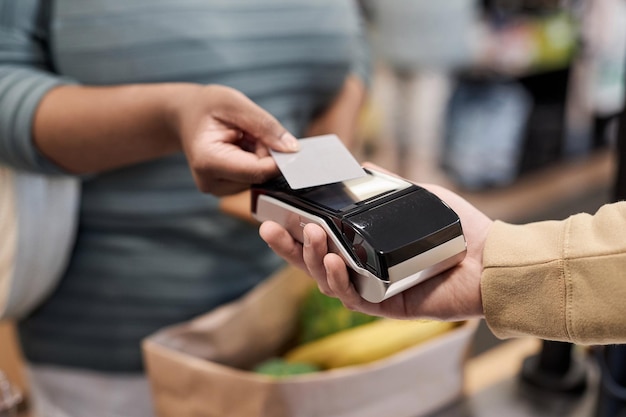 Onherkenbare zwarte vrouw die via creditcard in supermarkt betaalt