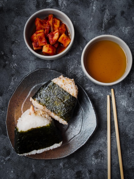 Onigiri Japans traditioneel eten, gestoomde rijst in driehoekige wrap met zeewier bovenaanzicht op grijs