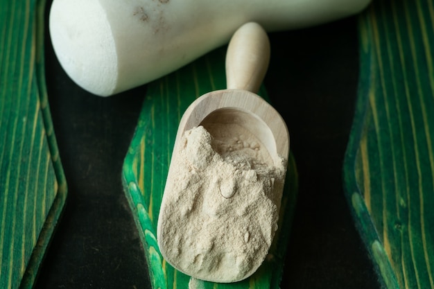 Onion powder in a wooden scoop on a colored background