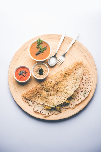 Onion rava masala dosa is een Zuid-Indiaas instant ontbijt geserveerd met chutney en sambar op een humeurige achtergrond. selectieve focus