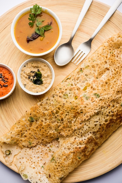 Onion rava masala dosa is een Zuid-Indiaas instant ontbijt geserveerd met chutney en sambar op een humeurige achtergrond. selectieve focus