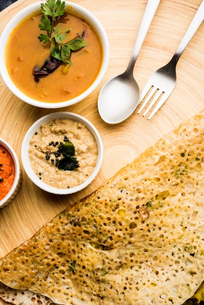 Onion rava masala dosa is a South Indian instant breakfast served with chutney and sambar over moody background. selective focus