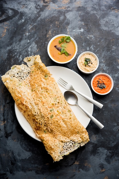 Photo onion rava masala dosa is a south indian instant breakfast served with chutney and sambar over moody background. selective focus