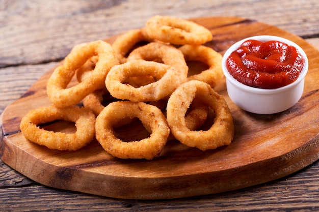 Foto anelli di cipolla con ketchup su tavola di legno