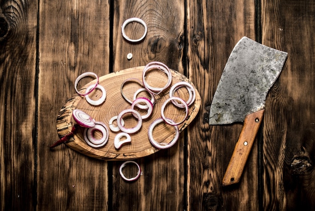 Photo onion sliced old hatchet on wooden table.