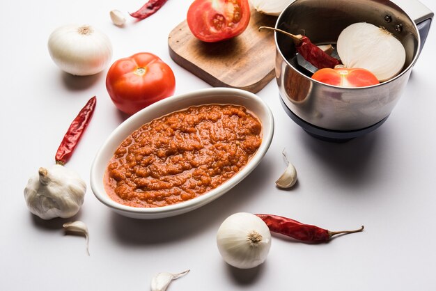 Masala o purea di pomodoro cipolla per salsa indiana, servita in una ciotola con tamatar crudo, pays e lehsun e peperoncino