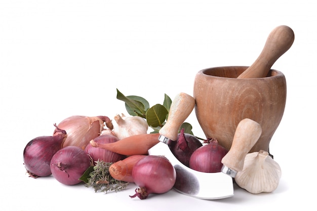 Onions, garlics and shallots with a manual chopper and pestle on white 