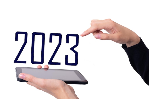 Online 2023 De hand houdt de telefoon horizontaal en wijst naar het nummer 2023 op een witte achtergrond