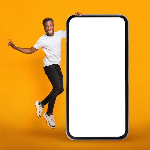 Online Ad Joyful Black Guy Jumping Near Huge Blank Cellphone