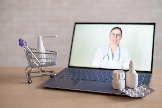 Online apotheek Vrouwelijke arts op online consult Computerapplicatie voor aankoop medicijnen met thuisbezorging Apotheker op laptopscherm en mini-winkelkarretje vol medicijnen