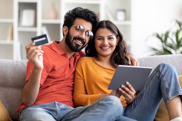 Online betalingen lachende Indiase echtgenoten met digitale tablet en creditcard